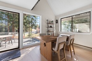 A modern kitchen with a wooden island, large windows, and a view of a forest. - Lakeview Retreat + Boat Slip & Waterfront Access (Coeur d'Alene)