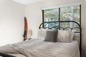 A bedroom with a bed, a window, a lamp, and a surfboard. - Lakeview Retreat + Boat Slip & Waterfront Access (Coeur d'Alene)