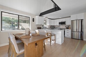 A modern kitchen with a central island, white cabinetry, and stainless steel appliances. - Lakeview Retreat + Boat Slip & Waterfront Access (Coeur d'Alene)