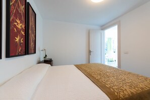 Una habitació d'hotel amb un llit, una porta que dona a un balcó i dos quadres penjats a la paret.