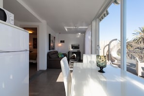 A modern living room with a dining area, a television, and a view of the outdoors. - Holidays & Health in Finca Oasis - Apartamento 6 by Viilas Rivero (Telde)