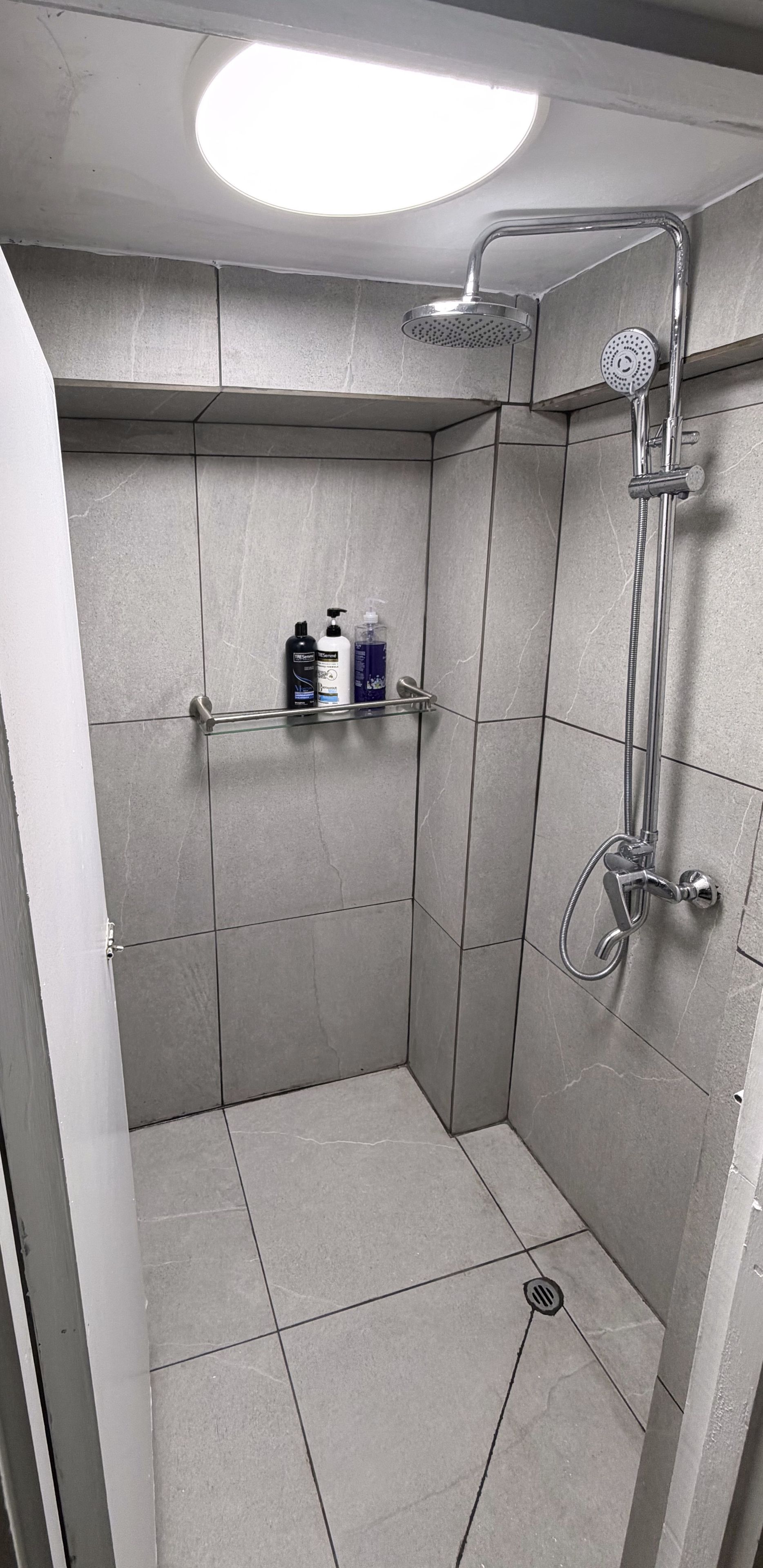 A modern shower with a handheld showerhead and a wall-mounted faucet.