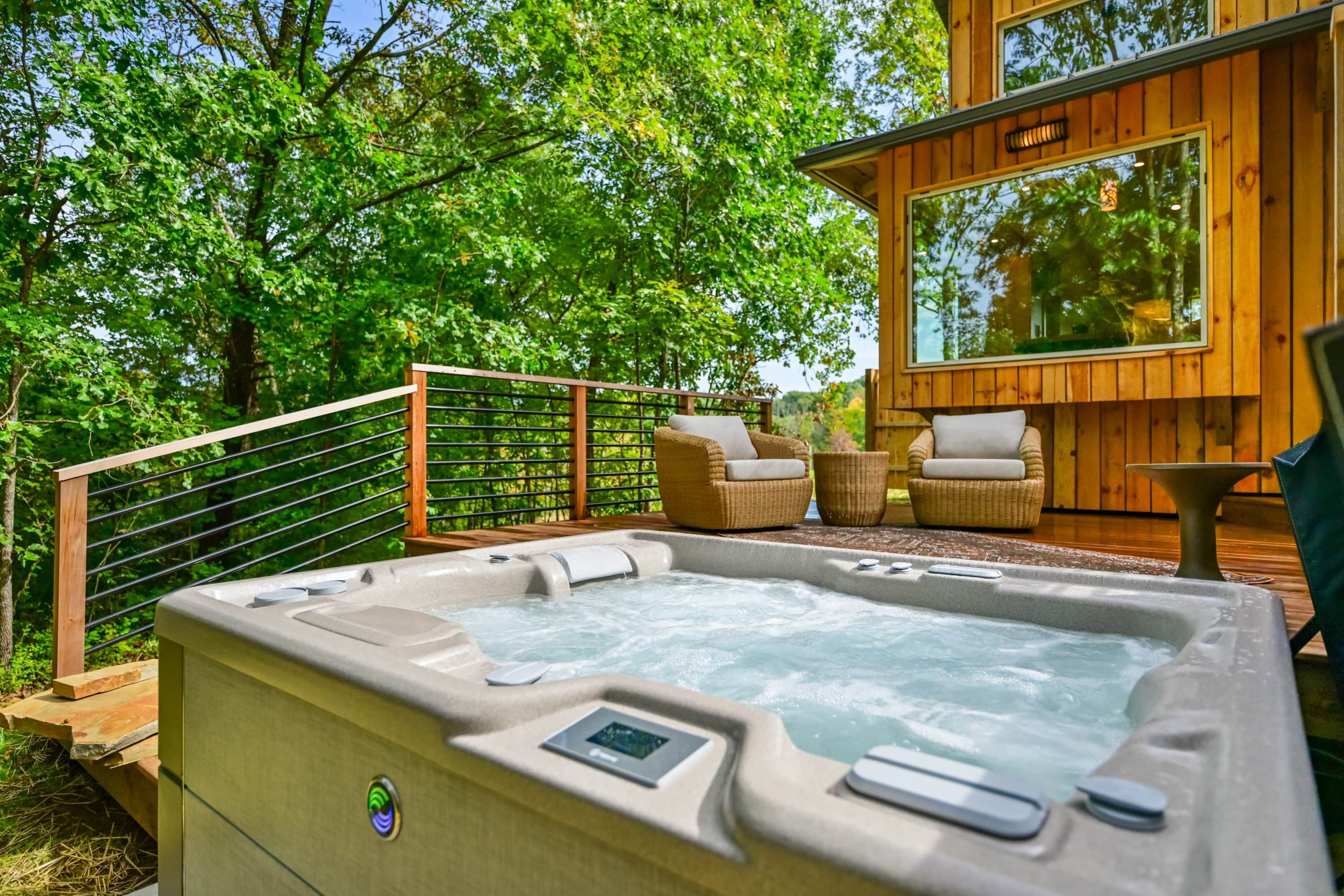 A hot tub with a control panel, surrounded by wicker furniture and a wooden deck.