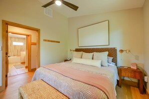 Une chambre à coucher comprenant un lit, des tables de chevet, une commode, une lampe fixée au mur et une porte donnant sur une autre pièce.