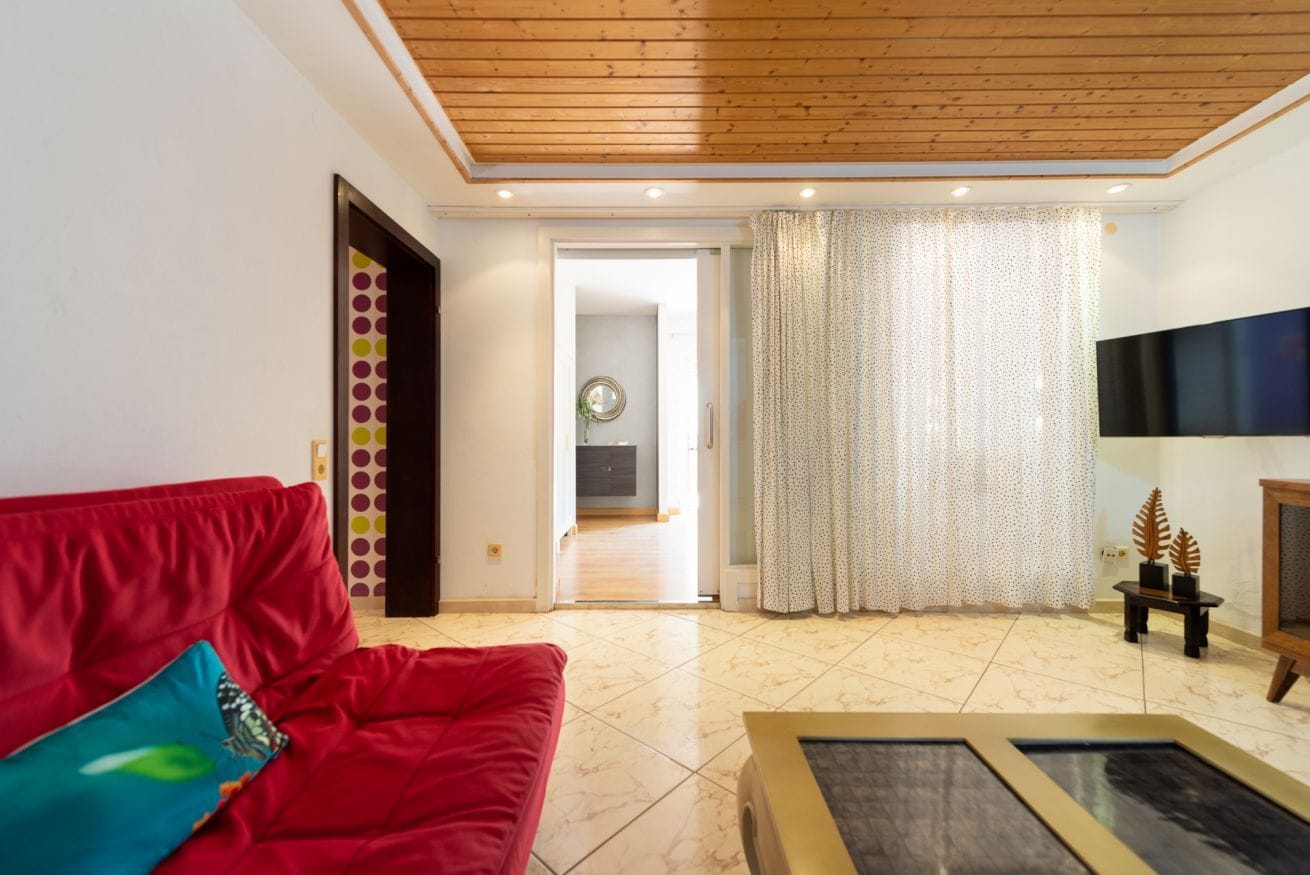 Una sala de estar con un sofá rojo, una mesa de centro y un techo de madera.