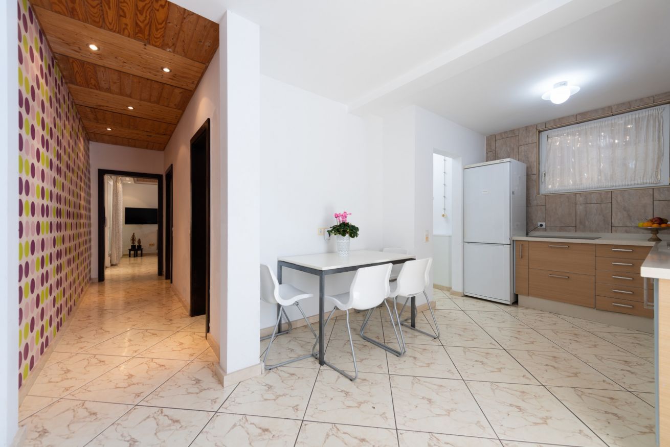 Una cocina moderna con un refrigerador blanco, una mesa de comedor con sillas y una isla de cocina.