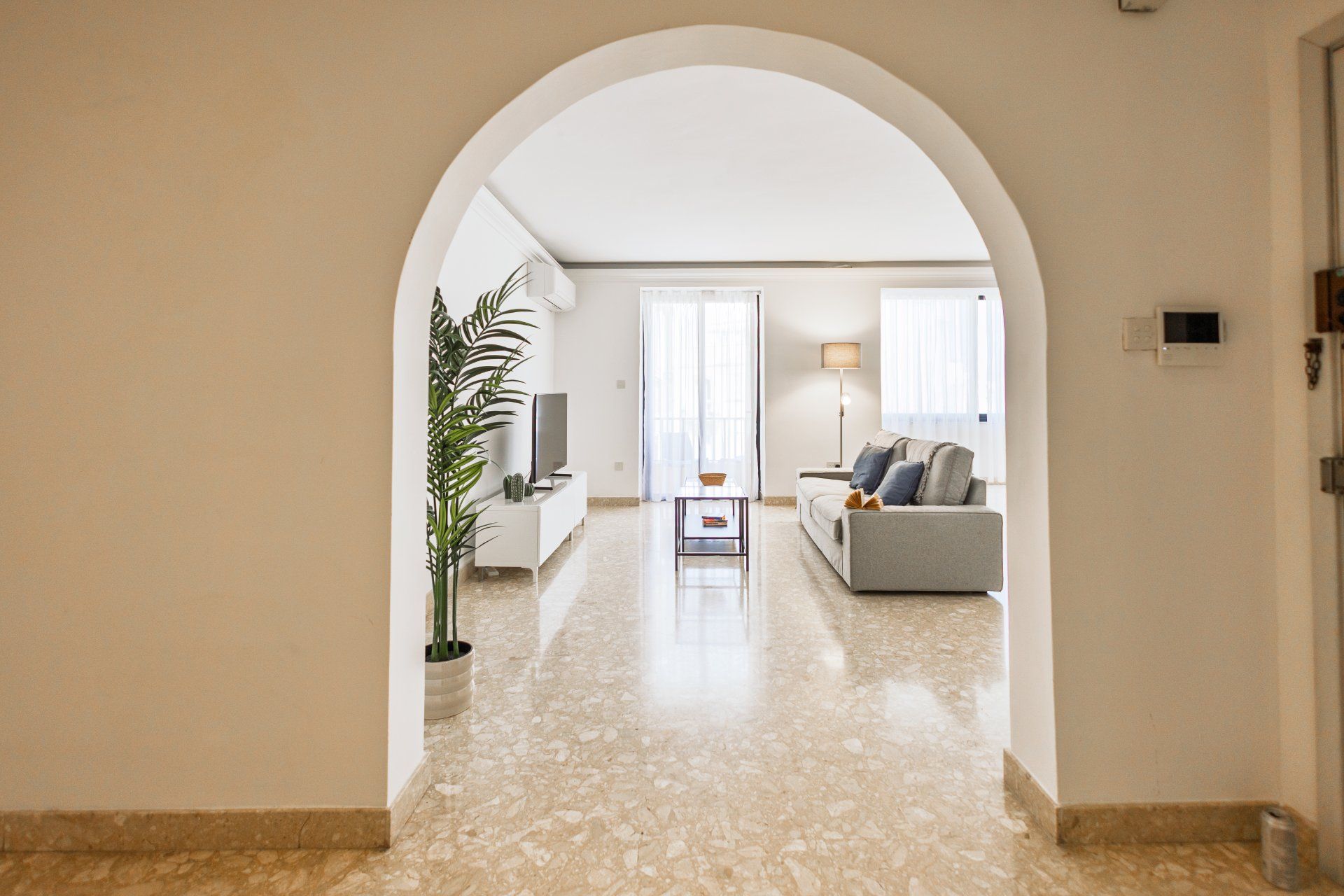A hallway leading to a living room with a sofa, a television, and a lamp.