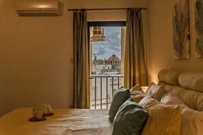A hotel room with a bed, a window with curtains, a view of a building with a dome, and an air conditioning unit on the wall. - Superlative 3BR in the Heart of Sliema (Sliema)