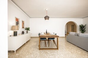 A dining area with a wooden table, chairs, a pendant light, and a white cabinet with a plant. - Superlative 3BR in the Heart of Sliema (Sliema)