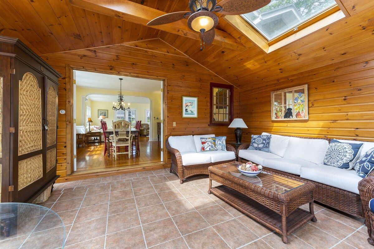 Un interior de madera con ventilador de techo, comedor y sala de estar con sofá y mesa de centro.