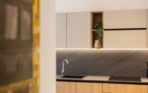 A modern kitchen with a built-in sink, wooden cabinets, and a small plant in a wooden shelf. - Charming 1BR Getaway, Great for Couples (Msida)