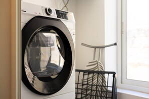 A front-loading washing machine in a laundry room with a window and a metal rack. - Clean and Convenient Apart, Central Location (Msida)