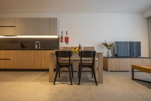 A modern kitchen with a dining area, wooden cabinets, a black countertop, and a flat-screen TV. - Sunny Apartment, Cozy Comfort in Style (Msida)