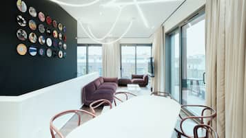 Una sala de estar moderna con una mesa blanca grande, un sofá púrpura y una pared decorada con diversos objetos circulares.