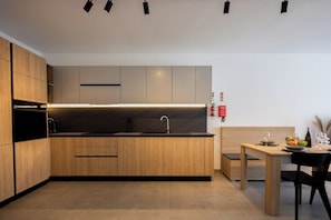 A modern kitchen with wooden cabinets, a built-in oven, and a dining area with a table and chairs. - Comfortable 1BR Flat With Balcony (Msida)