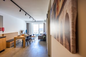 A modern interior with a dining area, a sofa, and a large painting on the wall. - Comfortable 1BR Flat With Balcony (Msida)