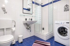 A modern bathroom with a toilet, sink, shower, and washing machine. - Belvedere Days Vienna Nights 1BR. (Vienna)
