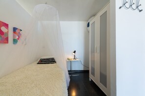 A bedroom with a bed, a bedside table with a lamp, a wardrobe, and wall art. -  Jardines del Cura - Apartamento 5 by Villas Rivero (Mogán)