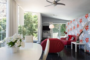 A modern living room with a dining area, a red sofa, a white table, and a ceiling fan. -  Jardines del Cura - Apartamento 5 by Villas Rivero (Mogán)