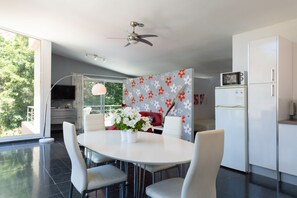 A modern kitchen with white cabinets, a microwave, and a dining area with a white table and chairs. -  Jardines del Cura - Apartamento 5 by Villas Rivero (Mogán)
