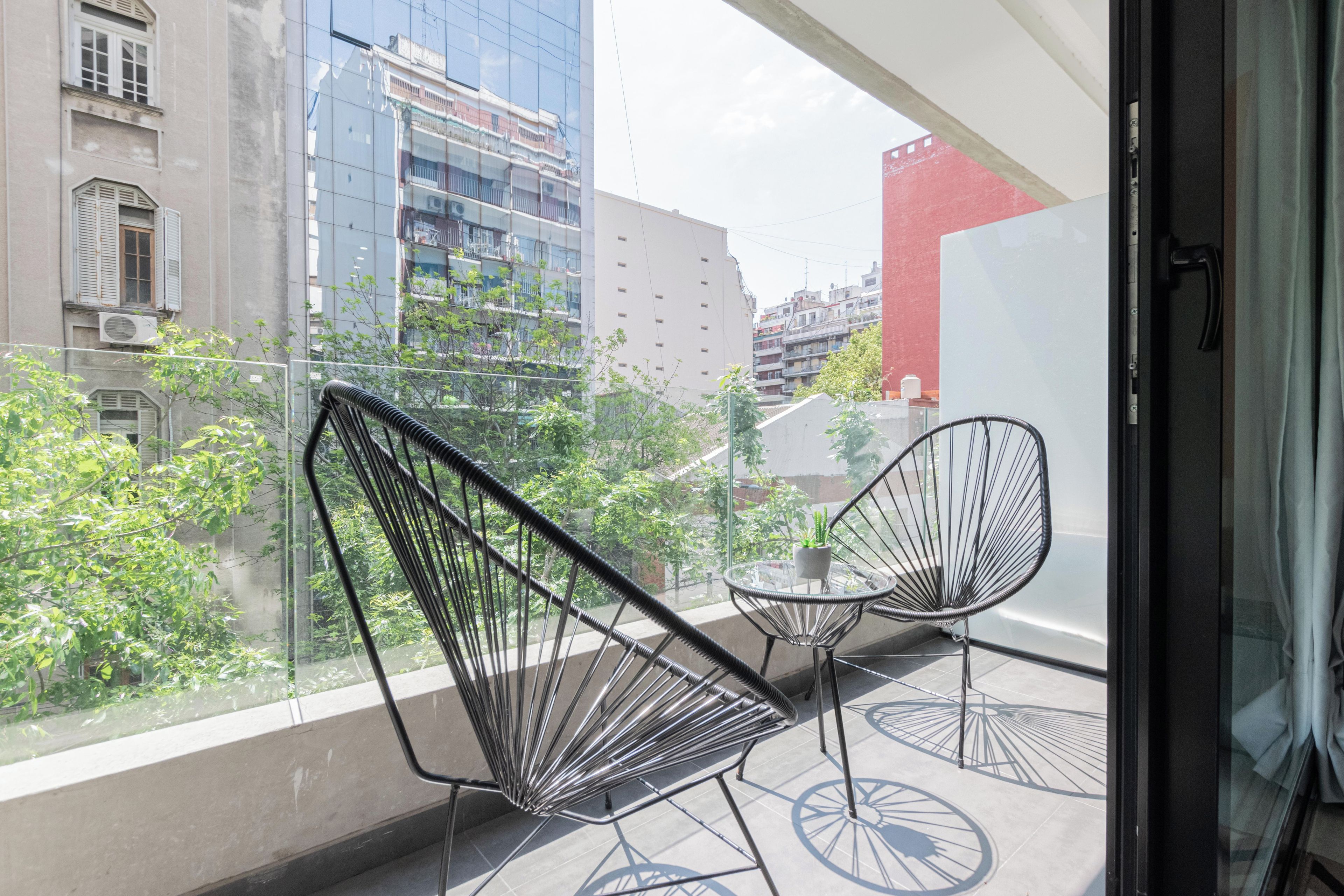 A balcony with two chairs, a small table, and a potted plant.