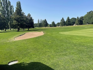 Camp de golf amb gespa ben cuidada, búnquers de sorra i arbres.