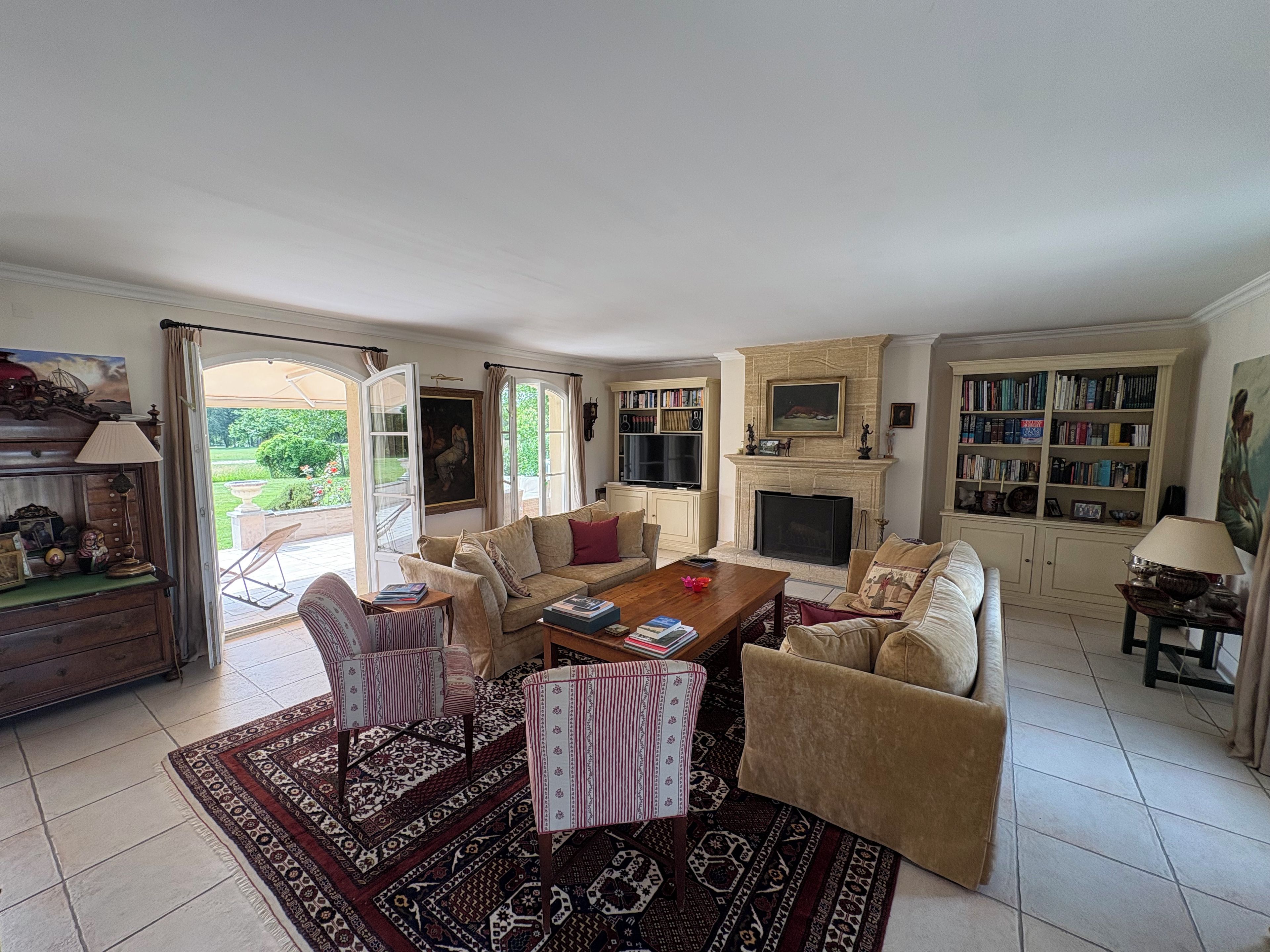 A spacious living room with a fireplace, a bookshelf, and a dining area with a coffee table.