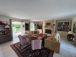 A spacious living room with a fireplace, a bookshelf, and a dining area with a coffee table.