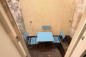 A small outdoor seating area with a table and chairs, a sign above the table, and a textured wall. - Alpine holiday home with balcony (Mont-Dore)