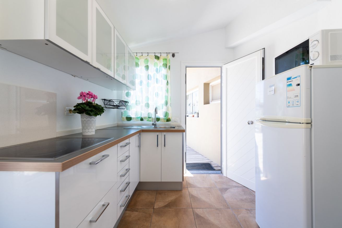 Una cocina moderna con armarios blancos, encimera de acero inoxidable y microondas integrado.