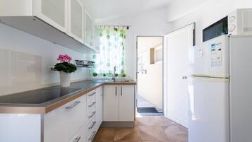 Una cocina moderna con armarios blancos, encimera de acero inoxidable y microondas integrado.