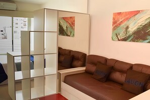 Ein modernes Wohnzimmer mit einem braunen Ledersofa, einem weißen Schrank und abstrakten Gemälden an der Wand.