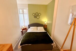 Une chambre à coucher avec un lit, une table de chevet, une lampe et un élément de décoration murale.
