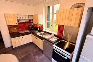 Eine kleine Küche mit Holzausstattung, einer Edelstahl-Spüle und einem eingebauten Backofen.