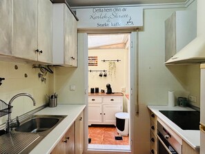 A compact kitchen with a sink, cabinets, and a sign above the door. - Casa Zeus by Rental Hero (Alcazares, Los)