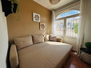 A bedroom with a large bed, a window with curtains, and a wall-mounted plant. - Casa Zeus by Rental Hero (Alcazares, Los)