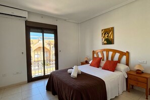 A bedroom with a bed, a nightstand, a painting, and a balcony door. - Casa Playa by Rental Hero (Alcazares, Los)