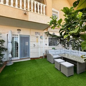 A courtyard with artificial green turf, a grey wicker sofa set, and a table. - Casa Sunset by Rental Hero (Alcazares, Los)