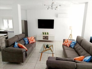 A modern living room with two sofas, a coffee table, a flat-screen TV, and a dining area in the background. - Casa Palma by Rental Hero (Alcazares, Los)