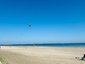 A beach with a clear sky, a few people, and a distant city skyline. - Casa Ribera Beach by Rental Hero (Narejos, Los)