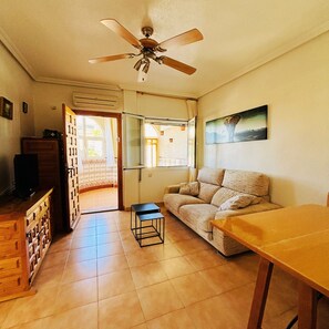 A living room with a sofa, a coffee table, a TV, and a ceiling fan. - Casa de Los Angeles by Rental Hero (Alcazares, Los)