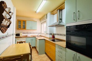 A kitchen with a microwave, stove, and cabinets. - Casa Los Narejos Beach by Rental Hero (Alcazares, Los)