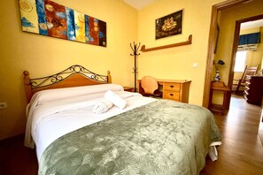 Ein Hotelzimmer mit Bett, Schreibtisch, Stuhl, Kleiderhaken und Bildern an den Wänden.