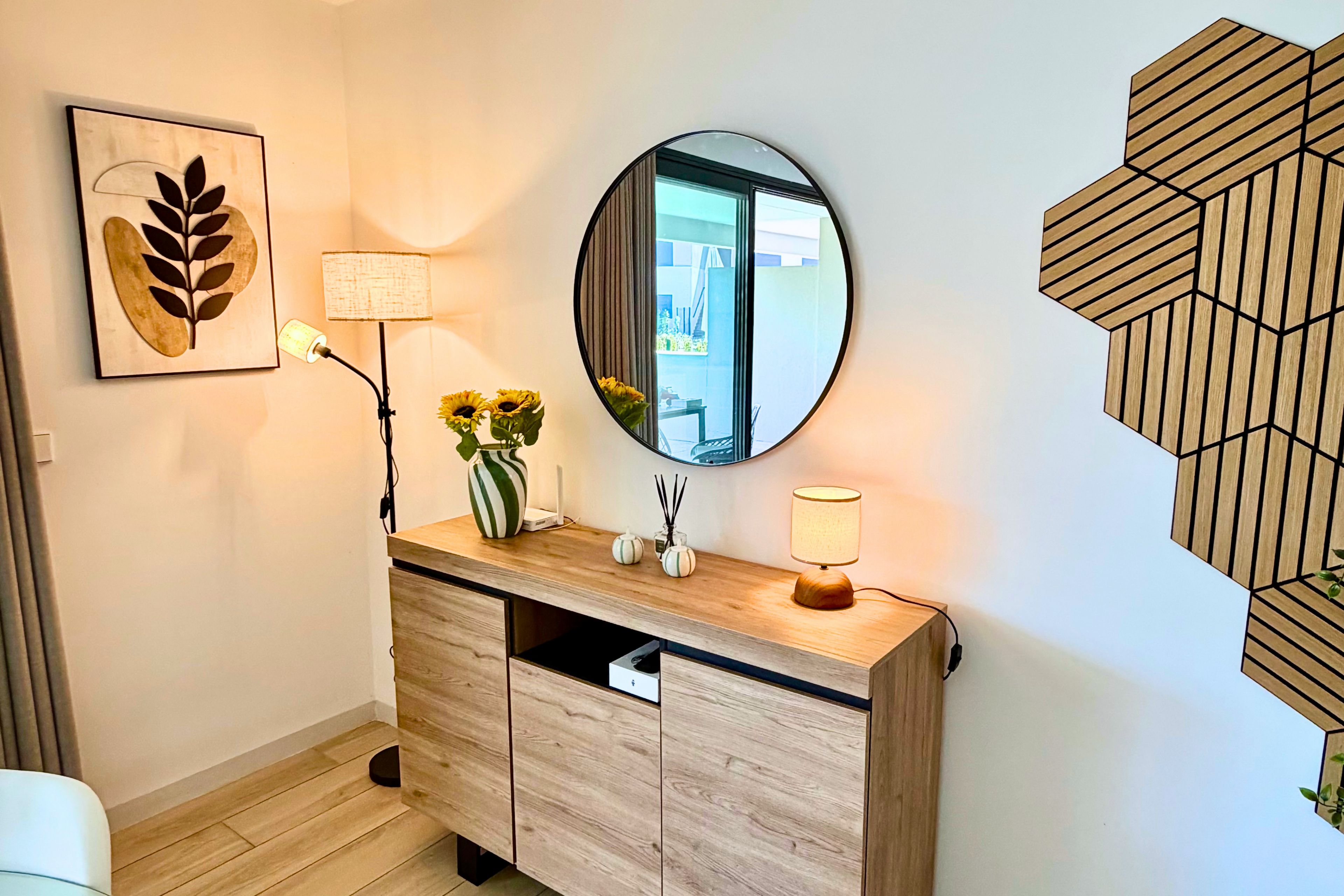 Un baño moderno con tocador de madera, un espejo redondo y un adorno de pared decorativo.