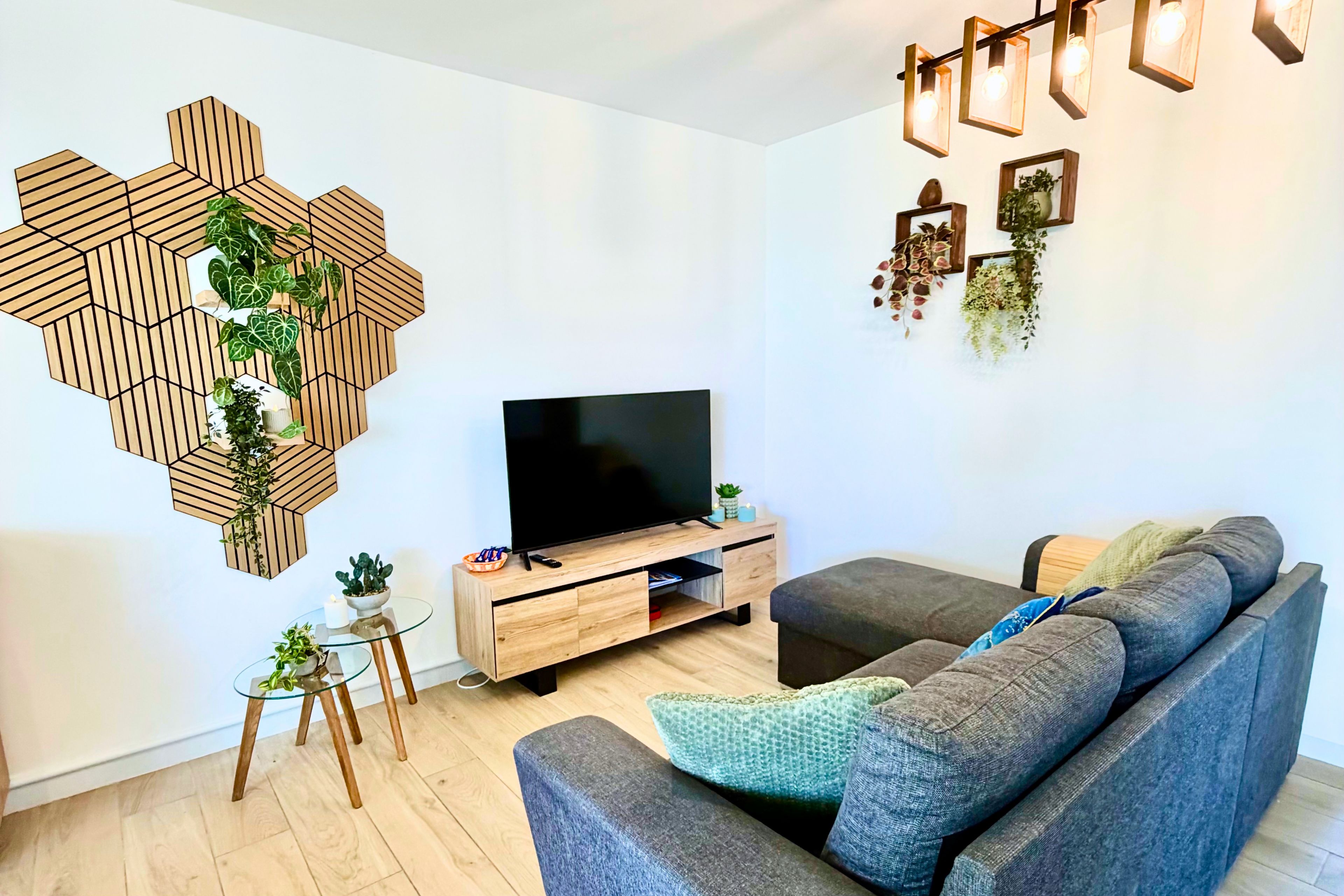 Un soggiorno moderno con TV a schermo piatto, divano, tavolino e decorazione murale in legno esagonale.