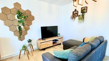 Un soggiorno moderno con TV a schermo piatto, divano, tavolino e decorazione murale in legno esagonale.