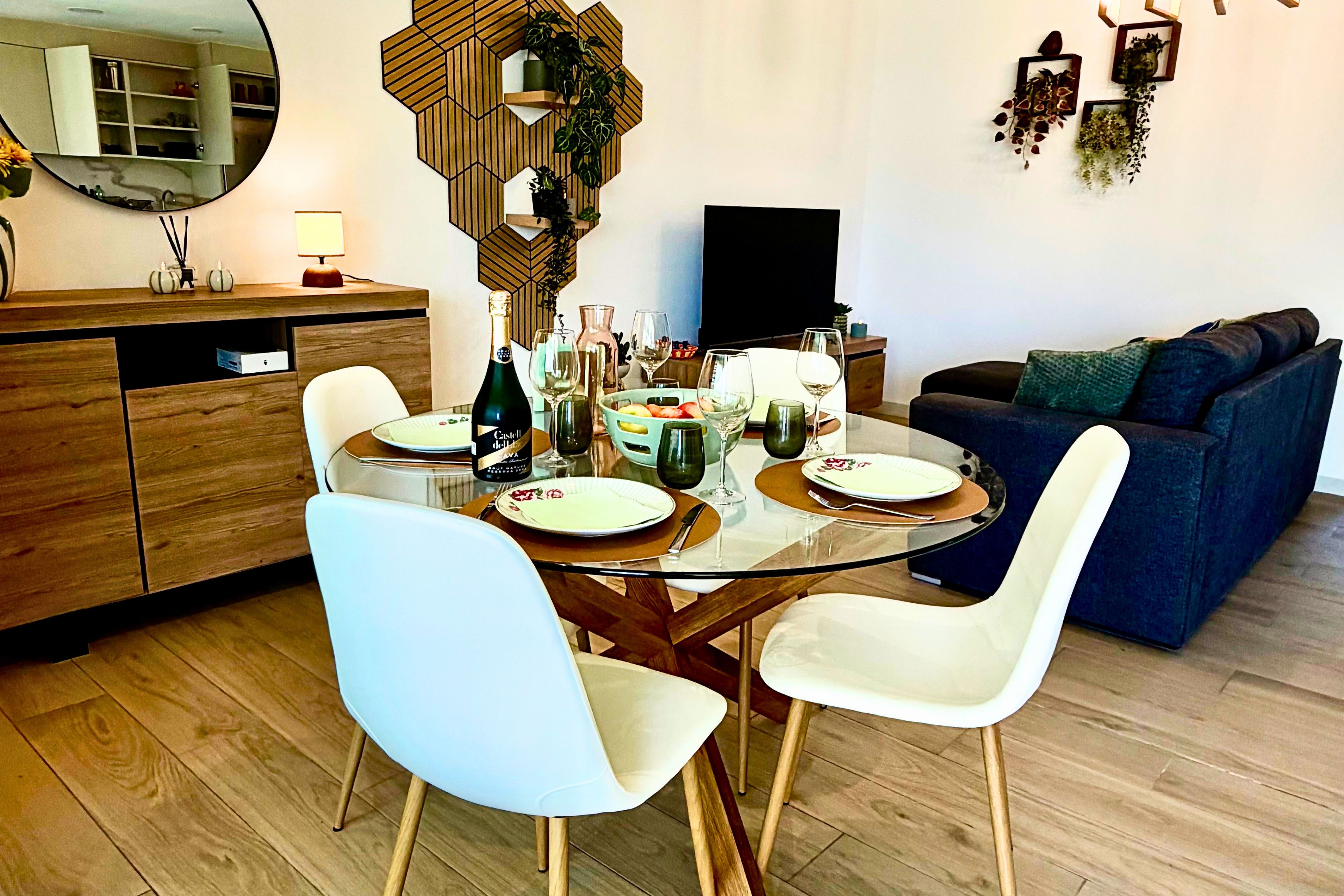 Un comedor moderno con una mesa de vidrio, sillas blancas y un armario de madera.