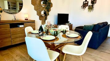 Un comedor moderno con una mesa de vidrio, sillas blancas y un armario de madera.