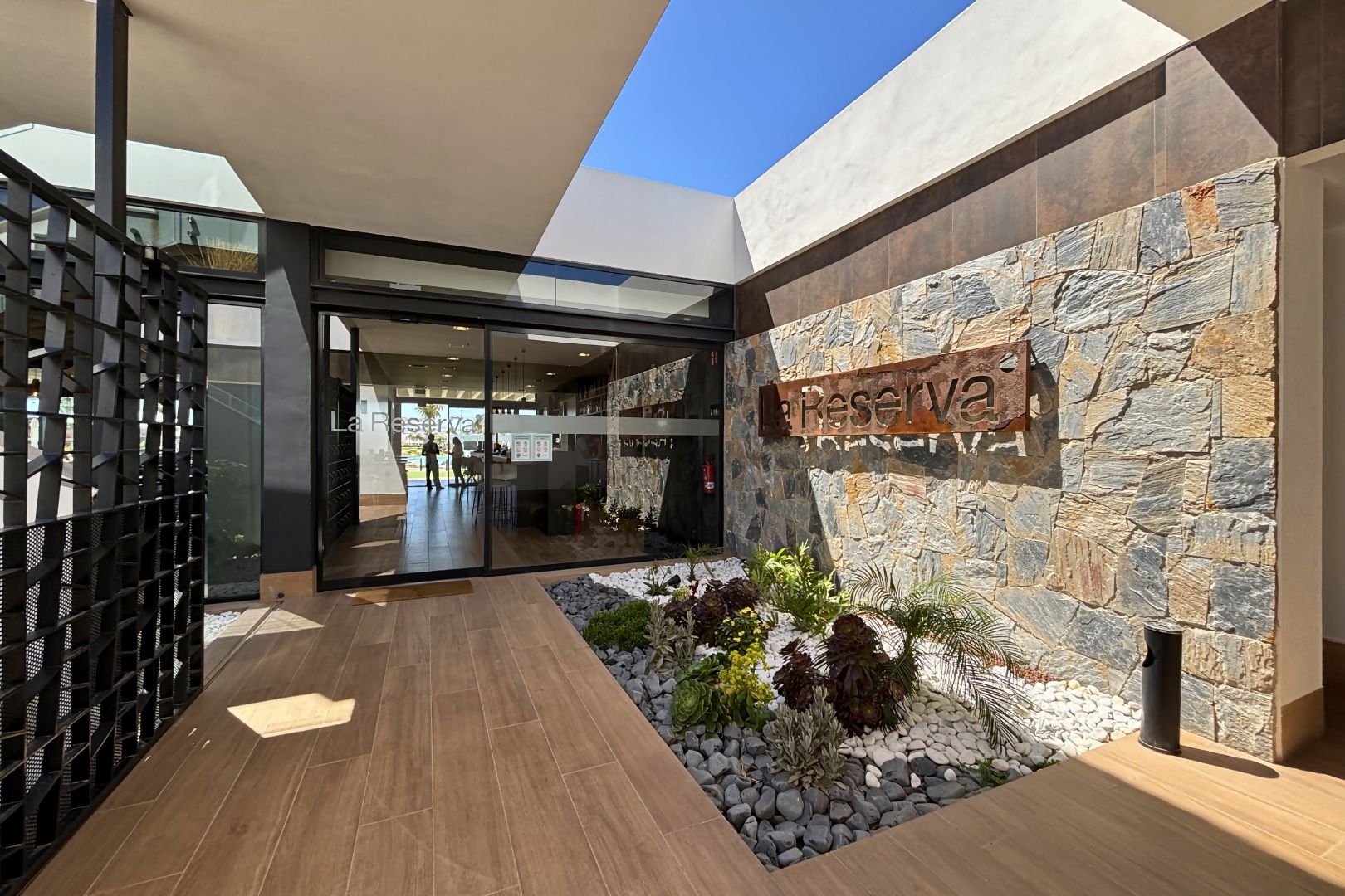Un moderno vestíbulo de hotel con pared de piedra, una recepción y una entrada de vidrio.