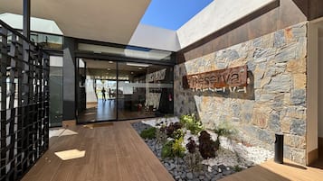 Un moderno vestíbulo de hotel con pared de piedra, una recepción y una entrada de vidrio.